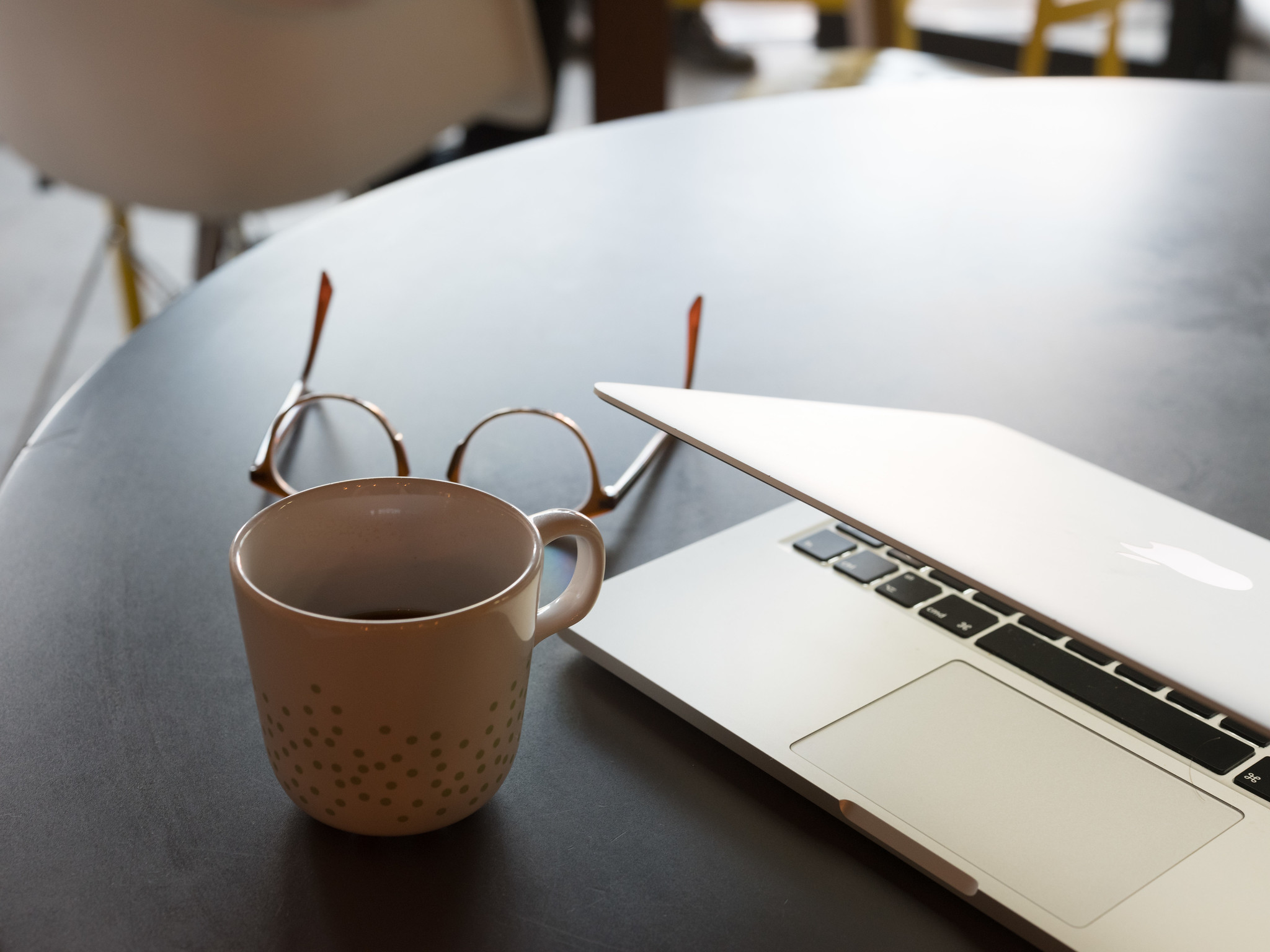 image of coffee mug and glasses next to a computer