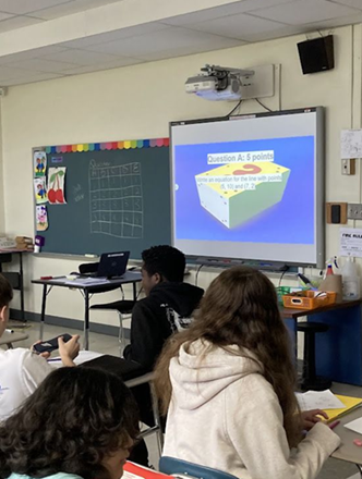 Students in a classroom looking at an image on a projector