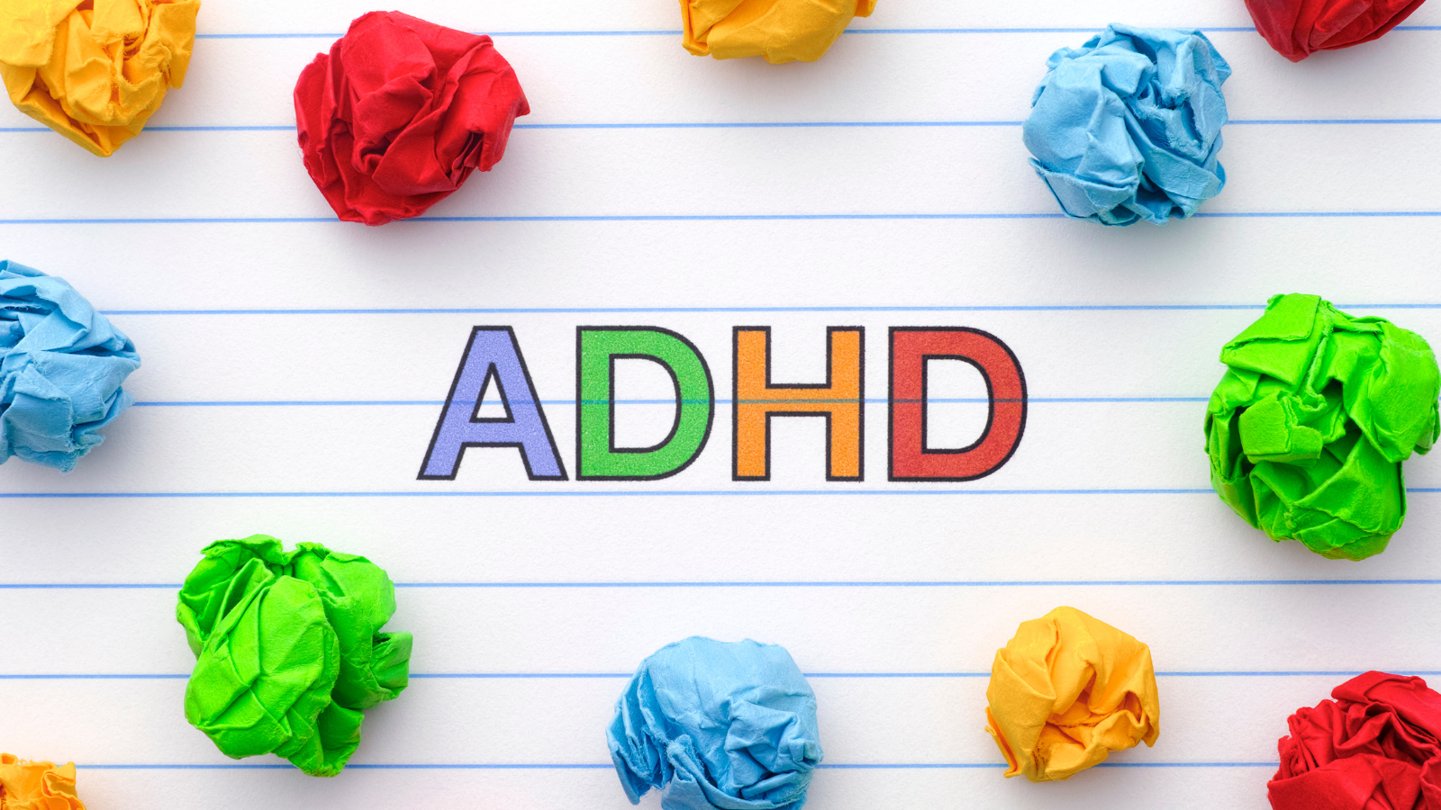 Lined notebook paper with colorful pieces of crumpled up paper and the acronym ADHD