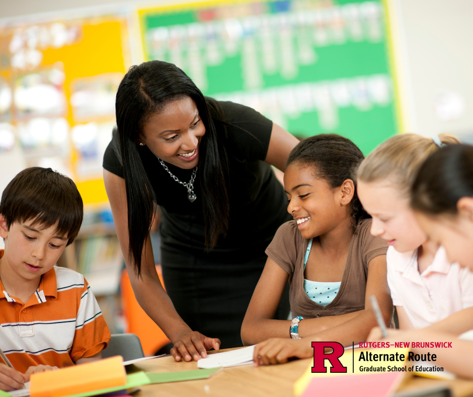 Teacher standing at table with students, explaining how to play a game