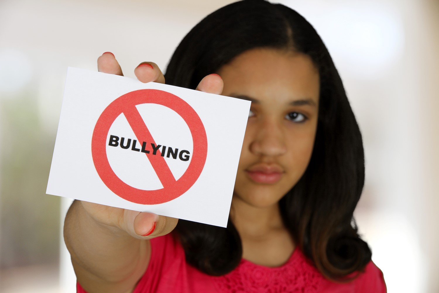 Woman holding a sign with the word 'bullying' crossed out