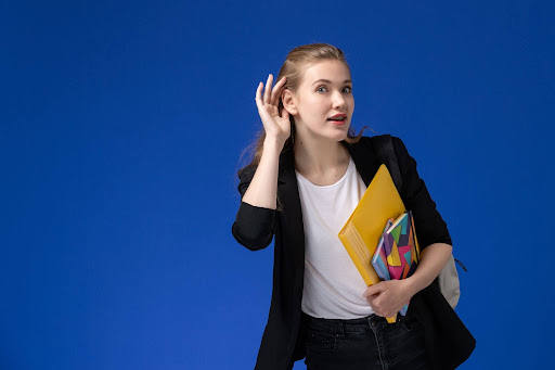 Woman holding folders with a hand to her ear