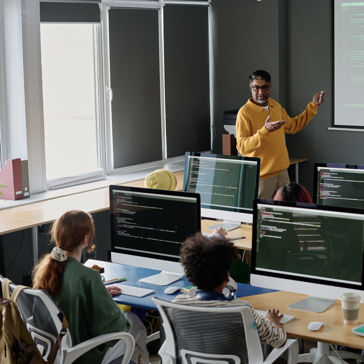 High school computer class with the teacher standing in front of a projection screen