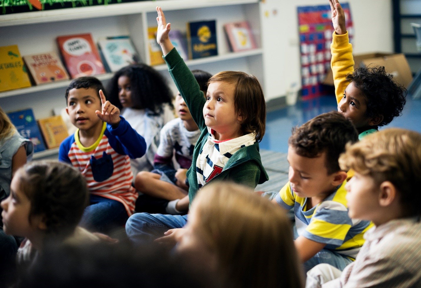 Group of elementary students sitting with hands raised