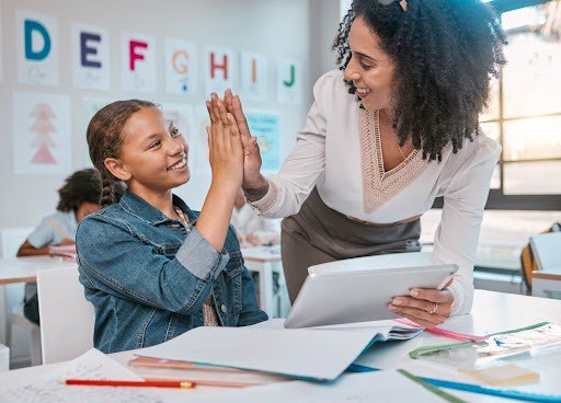 Woman with a student, giving her a high five