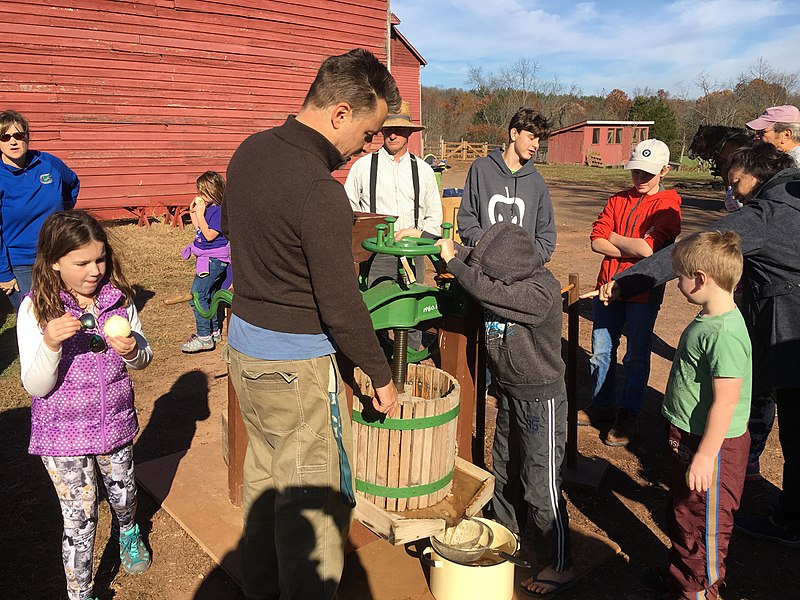 Students learning how to press cider at the Howell Living History Farm