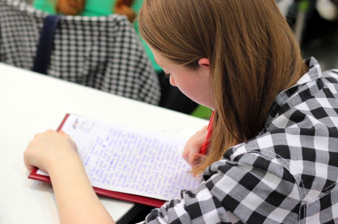 Student at a desk leaning over a notebook