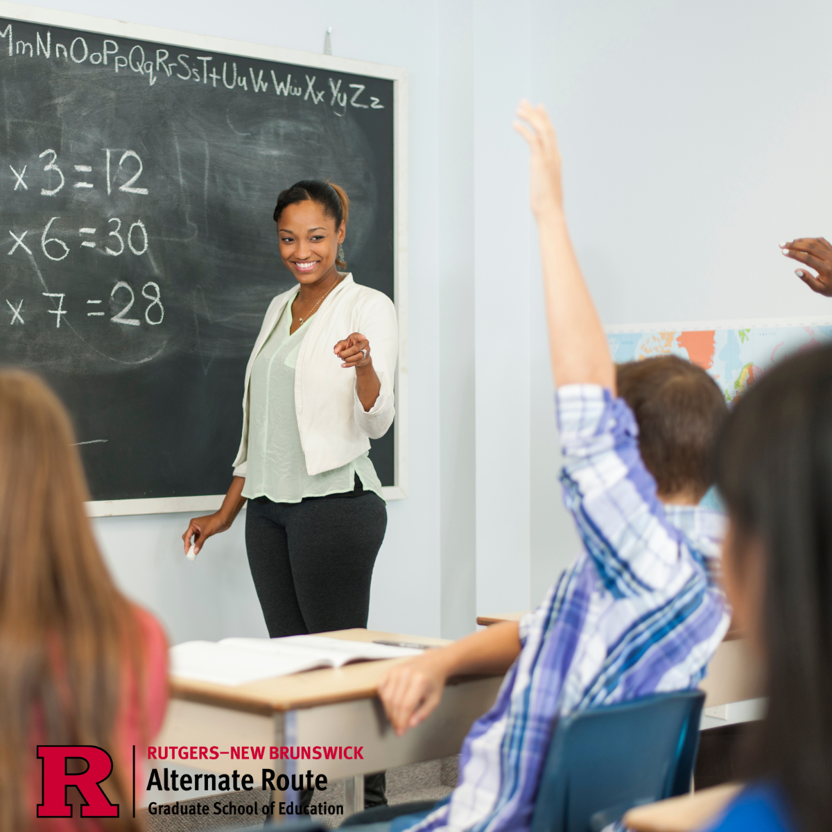 woman in front of a chalkboard with math equations, calling on one of her students with his hand raised