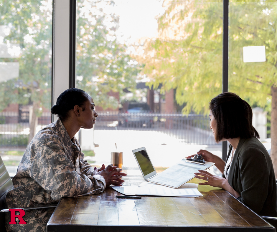 Two women--one in Army fatigues--at a table across from one another