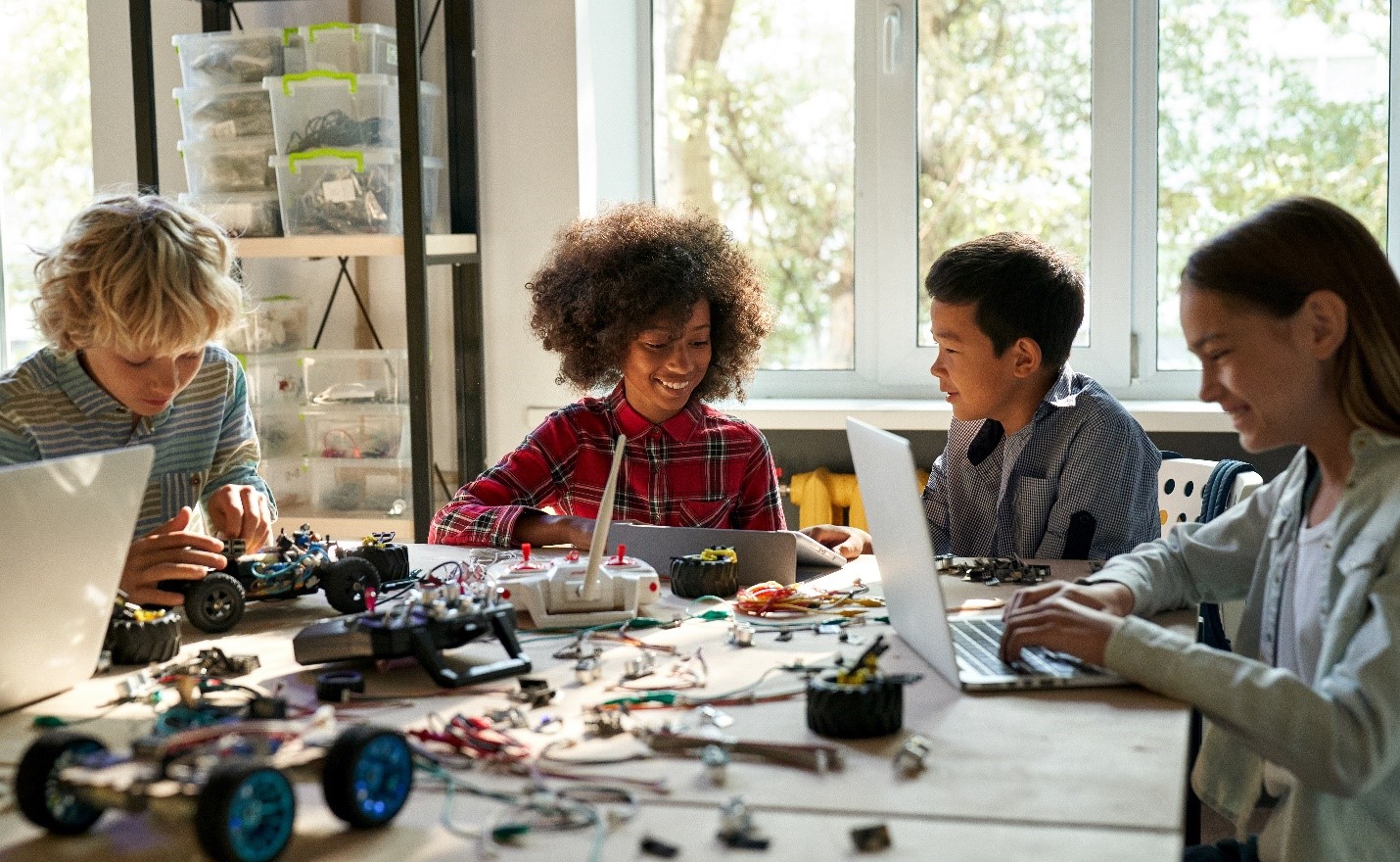 Students sitting at a table with computers and building bricks