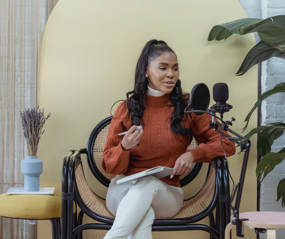 Woman sitting down in front of a microphone and recording a podcast