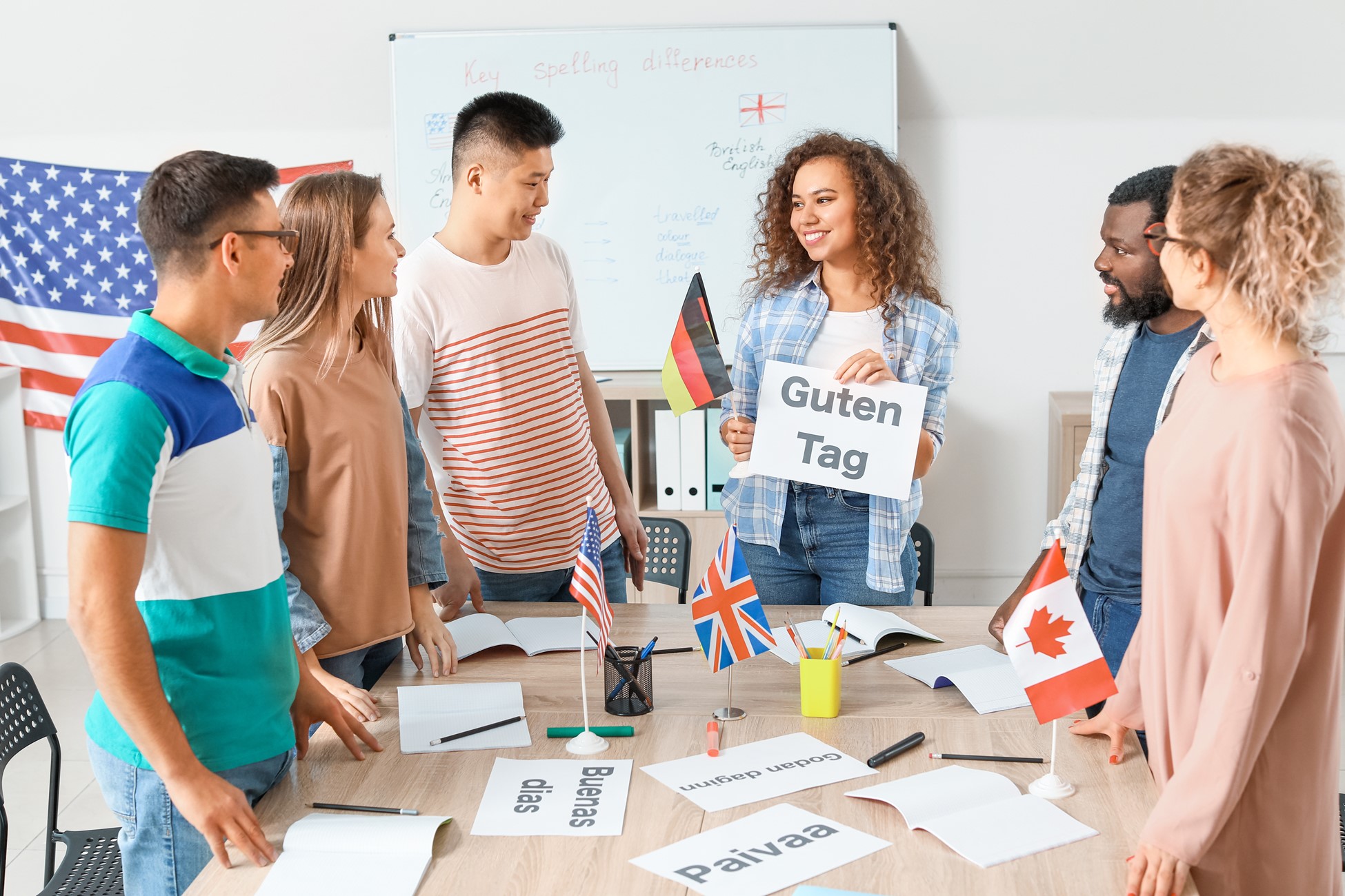 Group of students gathered around a table with language notecards and the flags for America, Germany, Great Britain and Canada