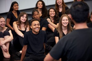 Dance teacher in front of a group of dance students wearing all black