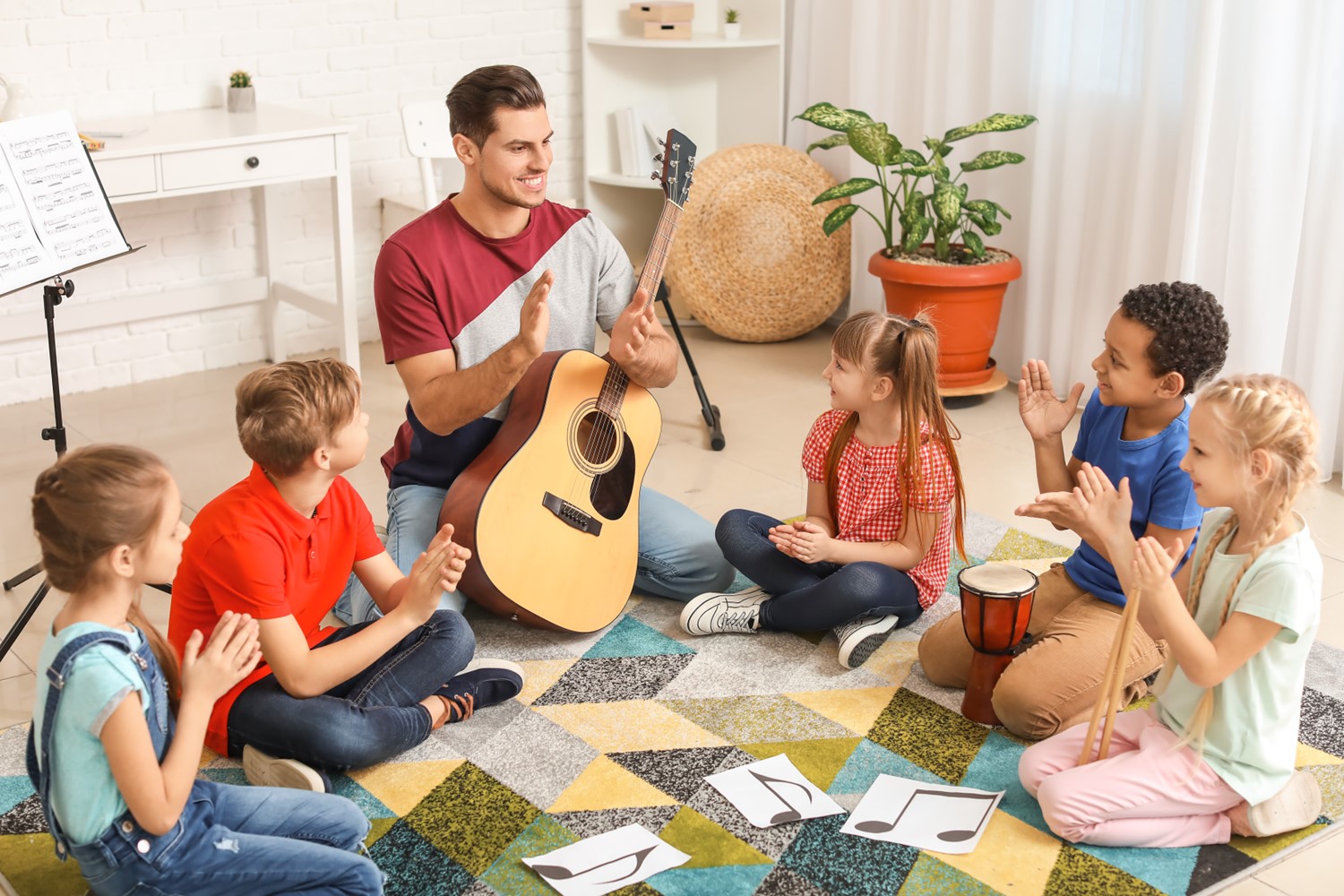 Students gathered around a teacher holding a guitar