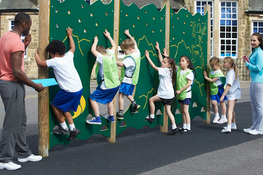 A group of students on a playground climbing wall 