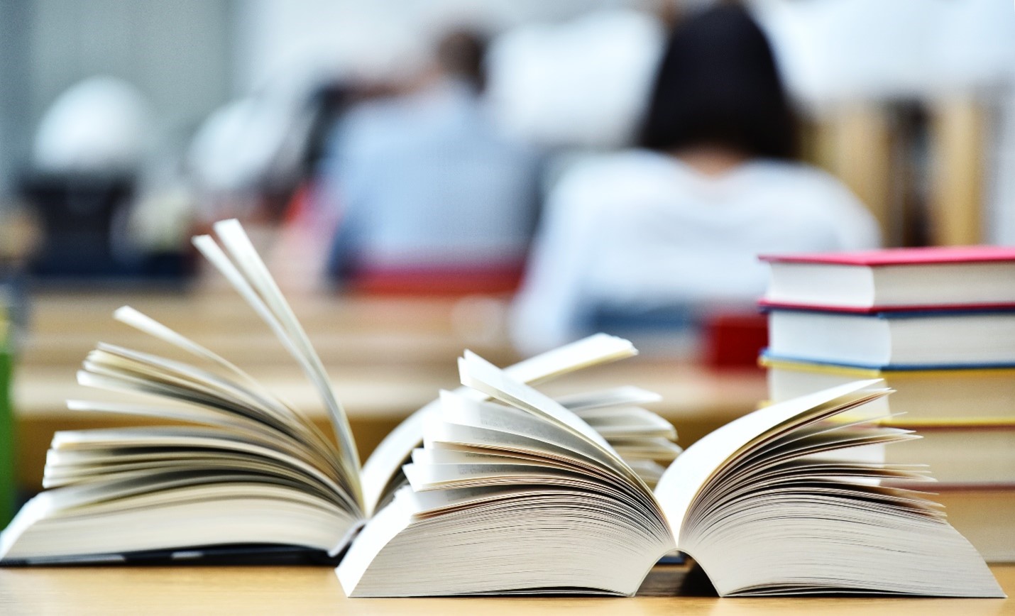 two open books in front of a stack of books