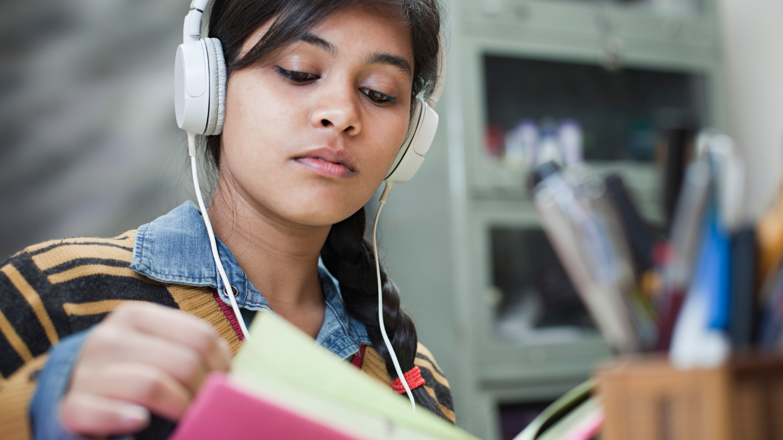 Teenager reading a book with headphones
