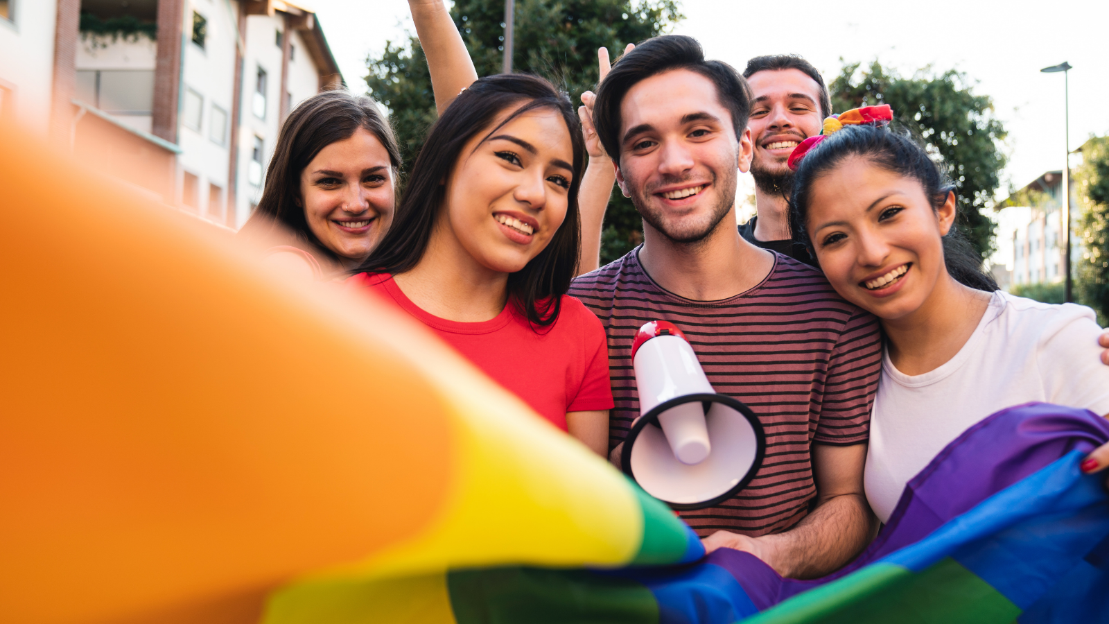 Group of young adults holding a pride flag