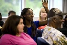 Group of people in a room with a woman with her hand raised