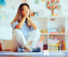 Female teacher sitting down, stressed, with her hands on her face