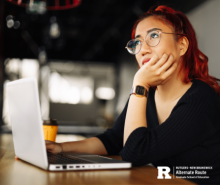 Woman at a laptop resting her chin in her hand and thinking