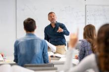 Man in front of whiteboard teaching high school students