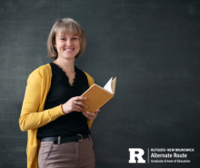 Woman holding a book in front of a chalkboard