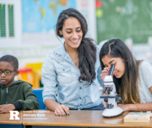 Teacher next to a student looking into a microscope