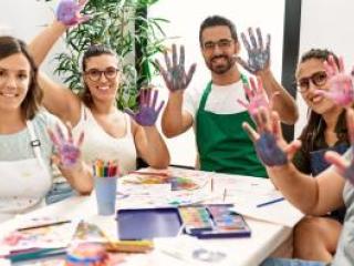 Group of art teachers around a table with paint on their hands