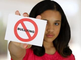Woman holding a sign with the word 'bullying' crossed out