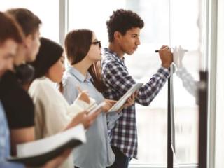 A group of diverse students at a whiteboard