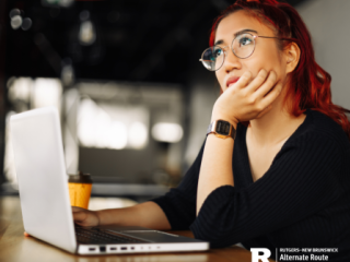 Woman at a laptop resting her chin in her hand and thinking