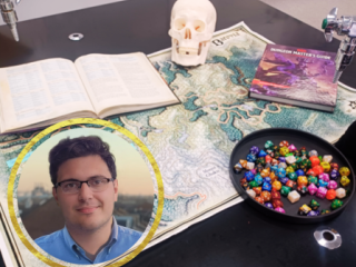 Set up of the game Dungeons and Dragons on a table with biology teacher Dennis' headshot in a frame in the corner