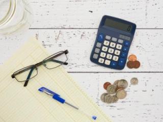 image of legal pad with glasses, a calculator, a pen and coins