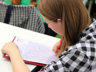 Student at a desk leaning over a notebook