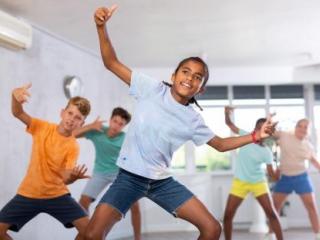 five elementary-age students in gym class doing dynamic stretching