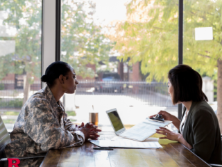 Two women--one in Army fatigues--at a table across from one another