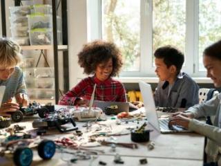 Students sitting at a table with computers and building bricks