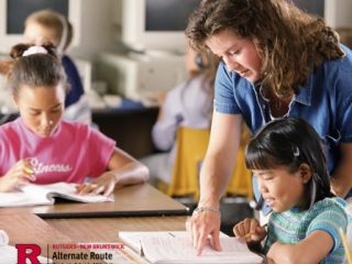 Substitute teacher at a table with students, helping an elementary-age girl with her schoolwork