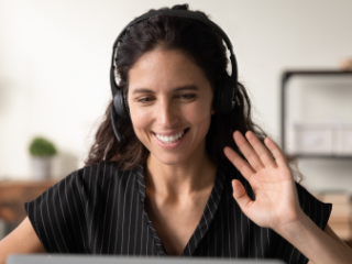 Woman with headphones in front of a computer waving