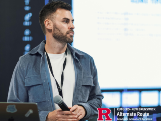 Conference speaker standing onstage, holding a microphone and looking at the audience