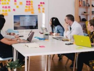 Group of diverse people around a computer monitor