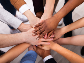 Diverse hands in a circle to signify teamwork