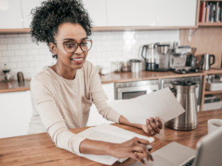 Black woman in font of a computer at her kitchen table