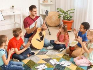 Students gathered around a teacher holding a guitar