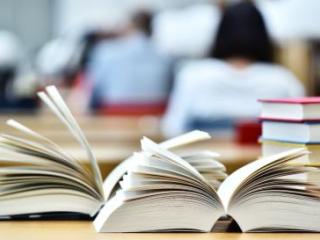 two open books in front of a stack of books